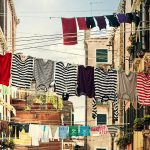 Vivid striped clothes hanging on lines between urban buildings.