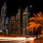 Stunning night view of Dubai's illuminated skyscrapers and palm trees with light trails from passing cars.