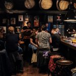 people sitting on bar chairs while drinking and talking