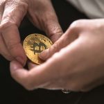 person holding round gold-colored Bitcoin