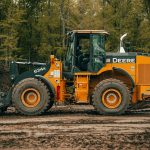 a tractor is parked in the dirt near a pile of dirt